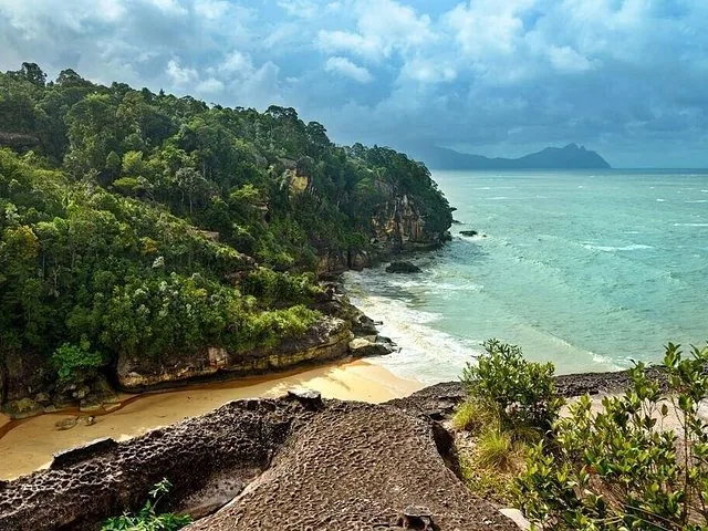 Eine felsige Klippe mit Blick auf einen Sandstrand und das Meer im Bako-Nationalpark.