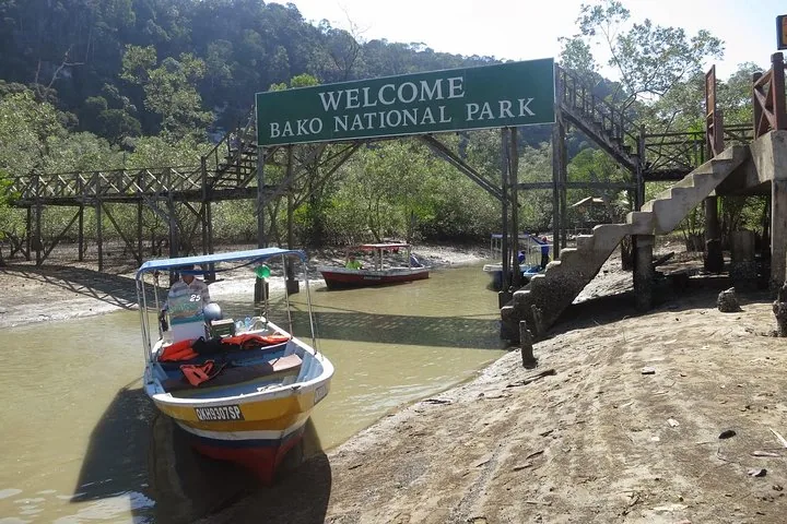 Boote an einer Holzbrücke und dem Willkommensschild zum Bako-Nationalpark.