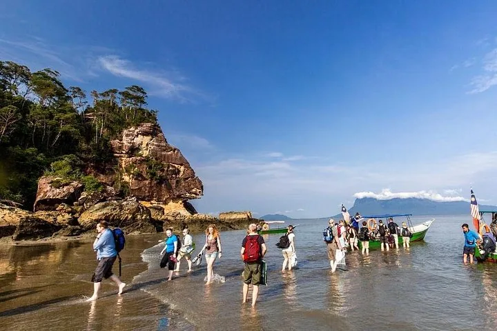 Touristen gehen an einem Sandstrand nahe dem Wasser im Bako-Nationalpark.